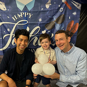 Two dads and their child celebrating a birthday