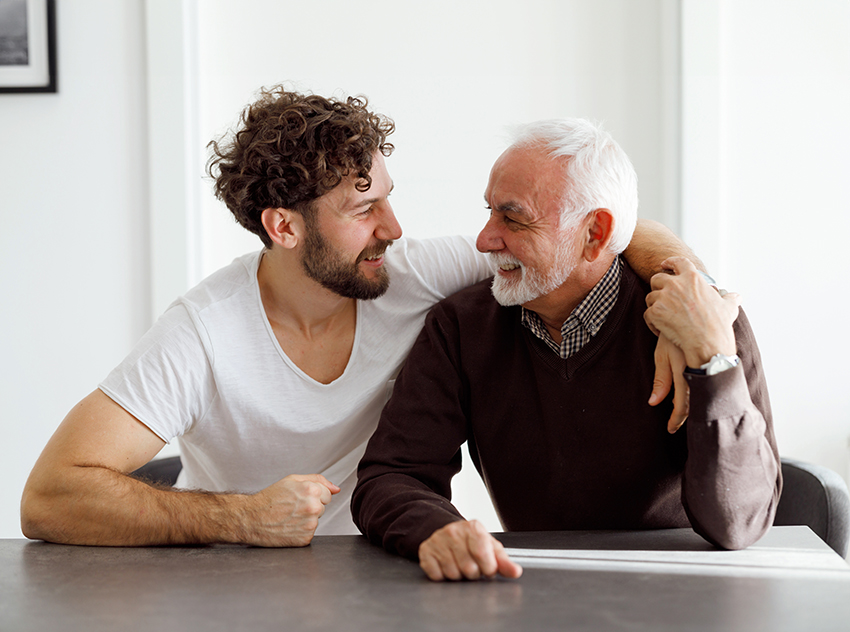 A younger man sitting with his arm around his father